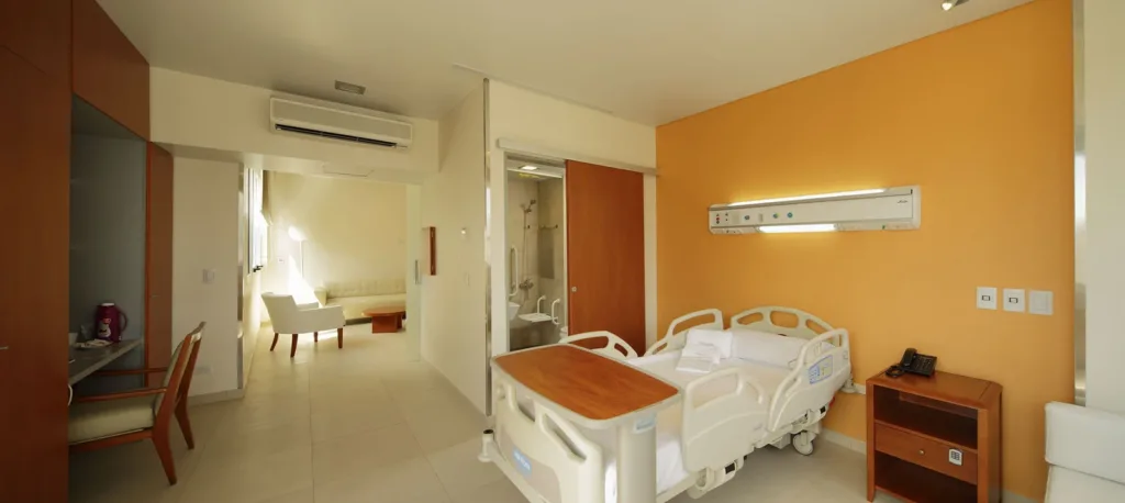 Suite vacía del Sanatorio Finochietto, con cama, baño privado y sector de estar.